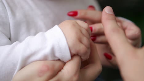 Caring-mother-with-baby,-Concept-of-love-and-family.-hands-of-mother-and-baby-closeup,-Hand-in-hand.-Mother-care.-Playing-with-baby-at-home.-Slow-Motion